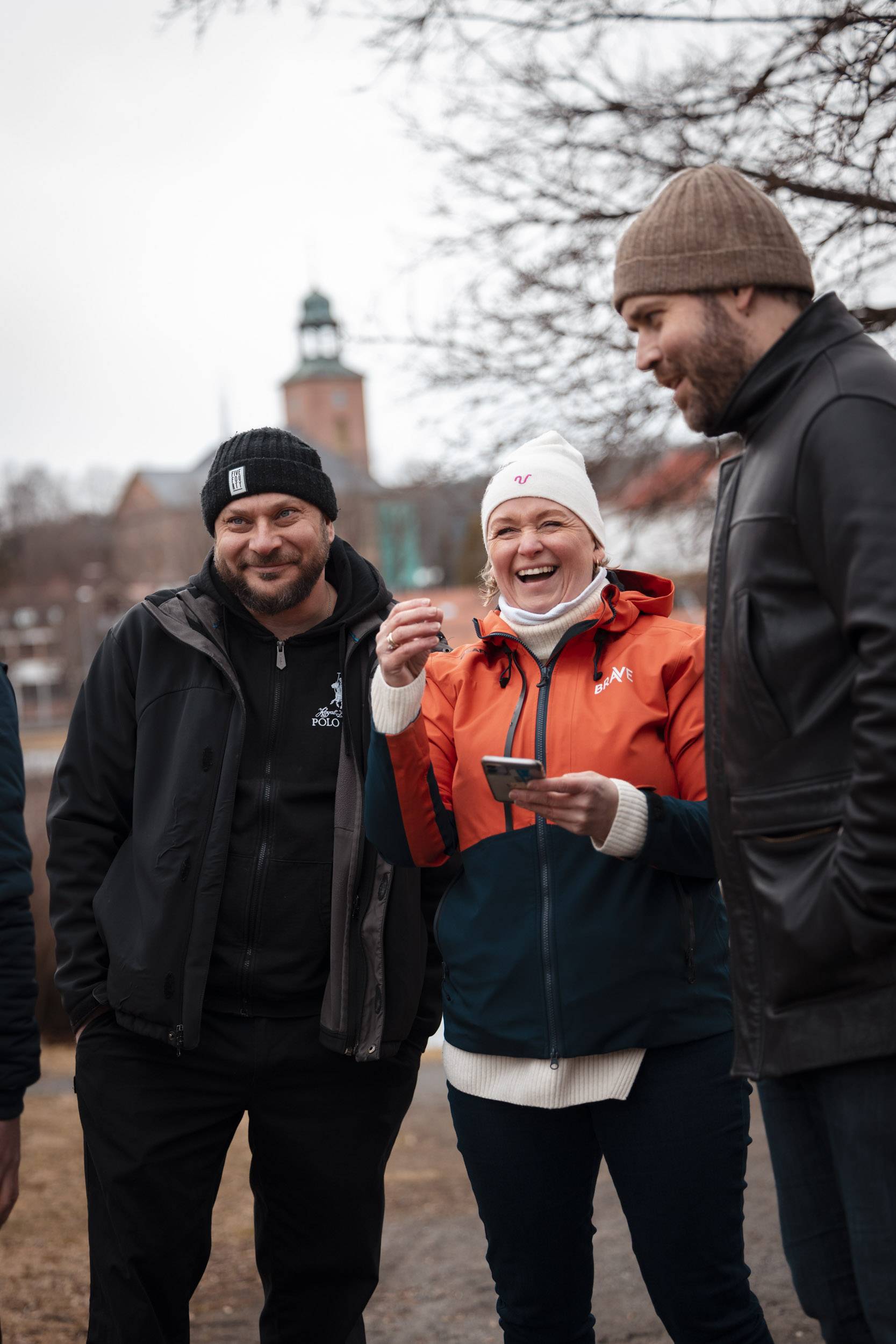 Jente iført rød våtdrakt, rød redningsvest og blå hjelp smiler nervøst til kamera